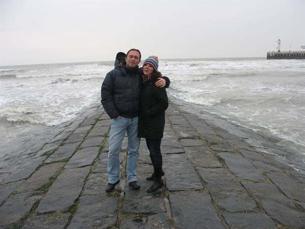 Couple hugging on a wet stone pier among crashing sea waves
