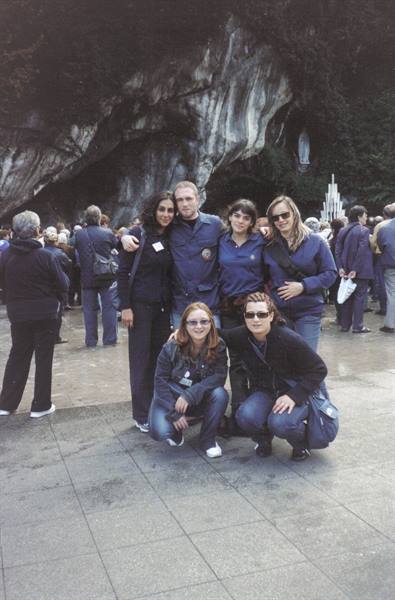 Group of people in blue uniforms in front of the Lourdes grotto