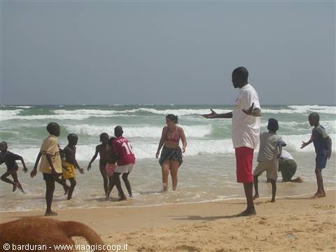 Children and tourists play in the waves on a sandy beach