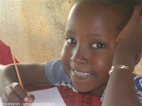 Smiling girl with silver bracelet writing with pencil in notebook, natural light