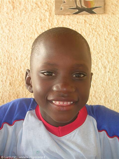 Smiling boy in light blue shirt against a yellow wall
