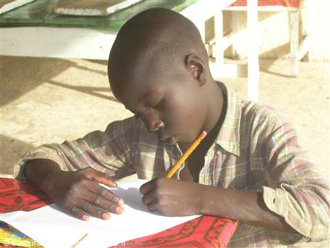 African boy writing with pencil on white paper, sunlight, plaid shirt