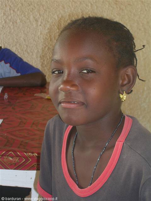 Smiling girl with gold earring and necklace near a red table