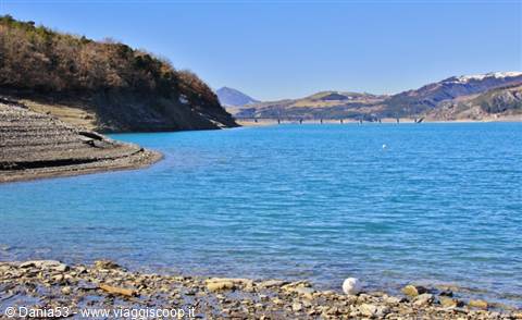 Turquoise waters of Lake Campotosto between rocky shores and Apennine mountains