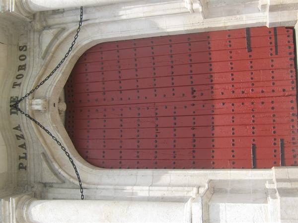 Plaza de Toros entrance: large red wooden door with iron chains