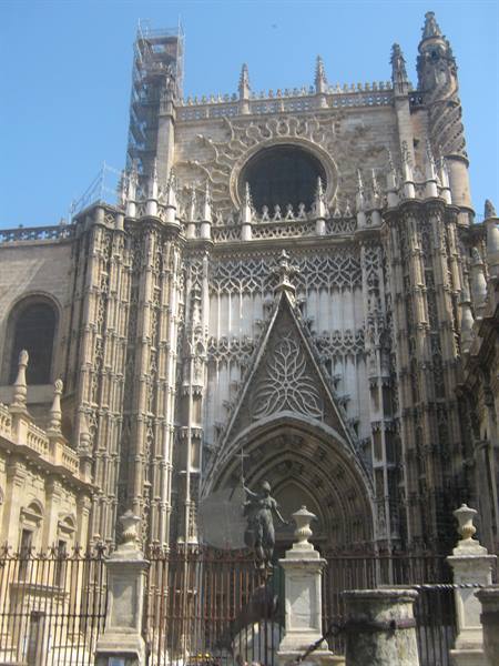 Gothic facade of Seville Cathedral with carved stone rose window and statue