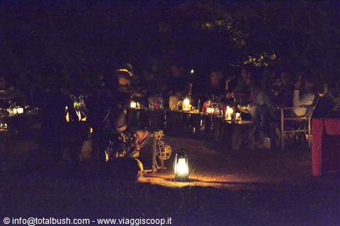 Night dinner at safari camp, tables lit by oil lanterns