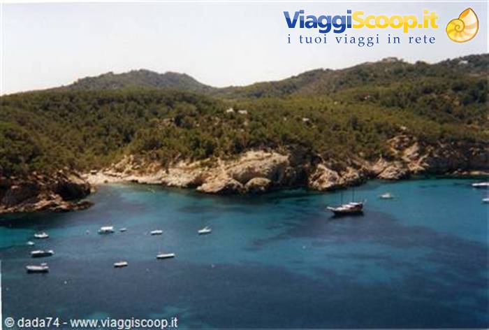 Boats anchored in turquoise cove surrounded by rocks and green hills
