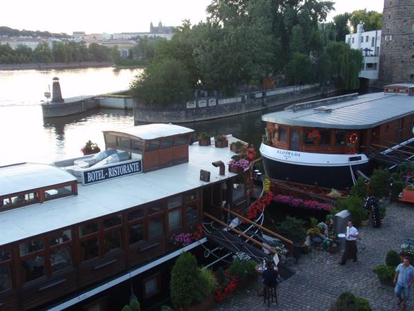 Restaurant boats moored on the Vltava in Prague, flowers and stone pier