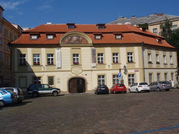 Yellow baroque palace with red roofs, parking cars, Prague