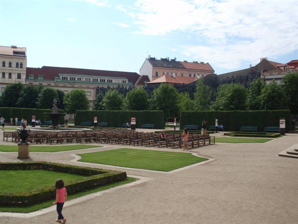 Child walks through baroque garden with hedges, chairs and fountain, Prague