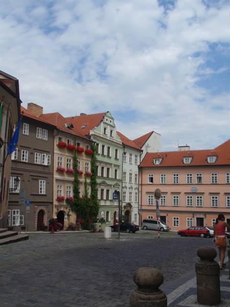Cobbled square with colorful houses, window flowers and red roofs in Prague