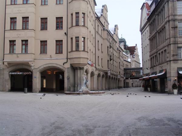 Snowy square in Munich with the Fischbrunnen fountain and the Karstadt department store