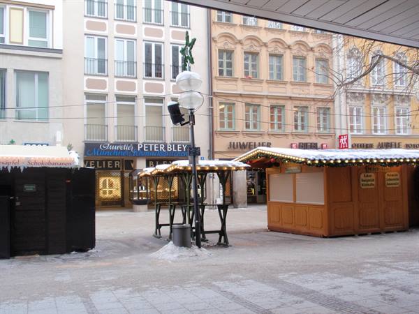 Closed wooden Easter market stalls on snowy square with historic buildings
