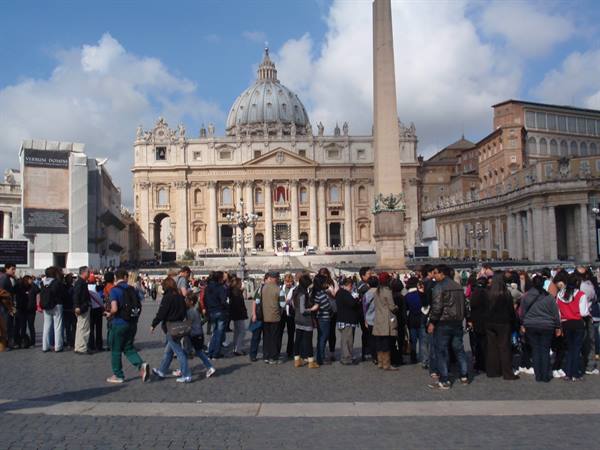 Crowds of tourists in St. Peter's Square facing the basilica and obelisk