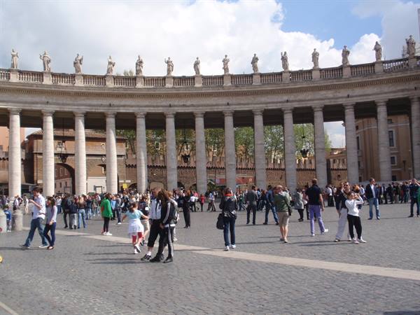 Tourists stroll under Bernini's colonnade in St. Peter's Square