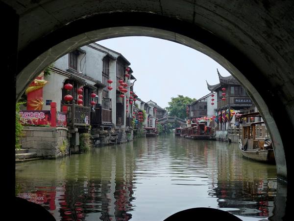Wuzhen canal seen through stone arch, red lanterns and wooden houses by water