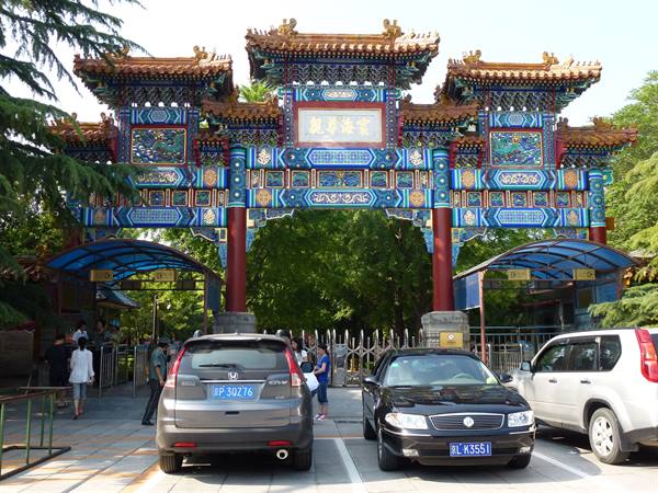 Ornate painted wooden gateway with cars parked in front