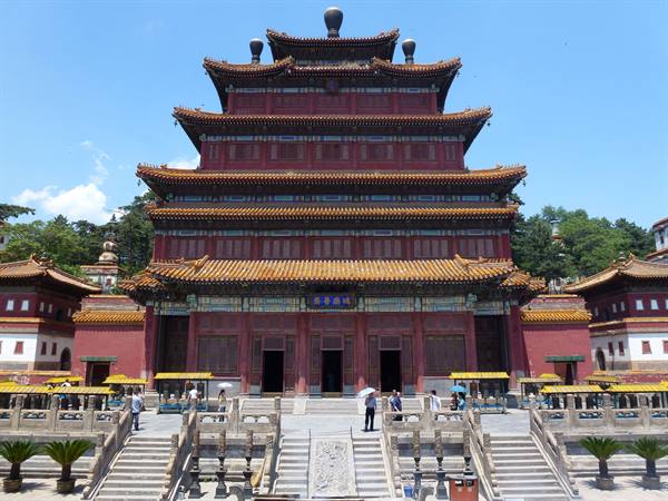 Tourists climb the stairs toward the red temple with golden roofs in Chengde