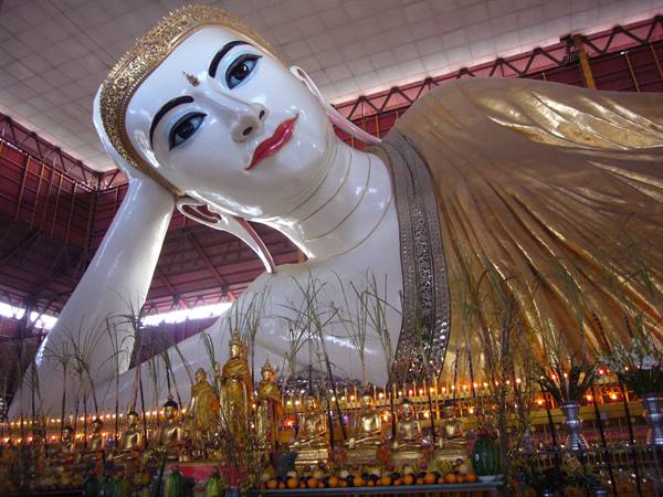 Golden reclining Buddha with offerings and candles, Shwethalyaung Pagoda in Bago