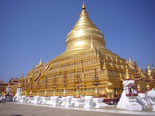Golden Shwezigon Pagoda in Nyaung-U under blue sky with white small stupas