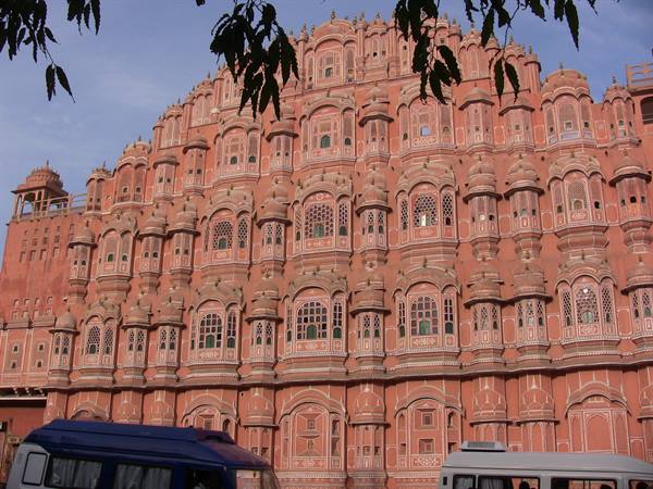 Hawa Mahal in Jaipur, pink facade of windows between buses and branches
