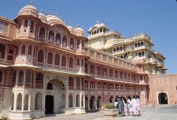 Women in saris walk across the courtyard of Jaipur's pink sandstone City Palace