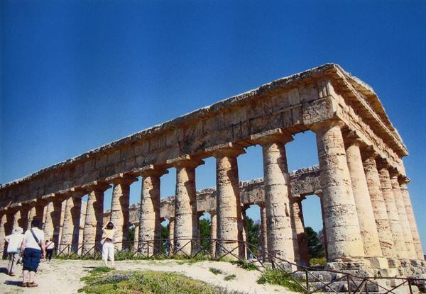Tourists in front of the Doric temple of Paestum under blue sky