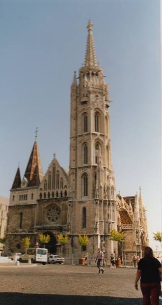 Tourists walk past Matthias Church in Budapest, pale stone under sunlight