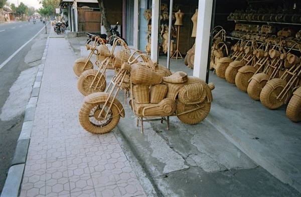 Wicker woven motorcycles displayed on the sidewalk outside the shop