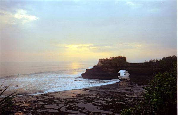 Tanah Lot temple on rock outcrop, ocean waves, golden evening light