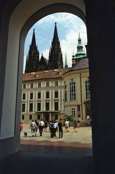 Tourists in Prague Castle courtyard beneath the gothic spires of St Vitus Cathedral