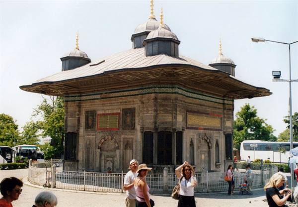 Tourists in front of the Ahmet III fountain in Istanbul, carved stone and lead roofs