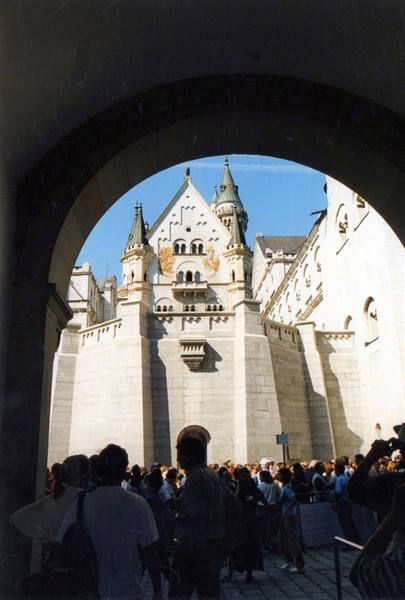 Tourists queuing under the stone archway of Neuschwanstein castle
