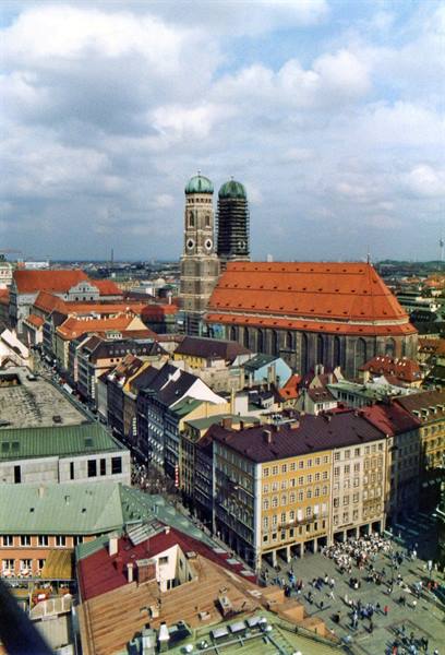 Frauenkirche's twin towers above red rooftops, crowds at Marienplatz, Munich