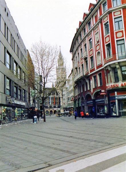 Square with red buildings and shops, Munich New Town Hall in the distance