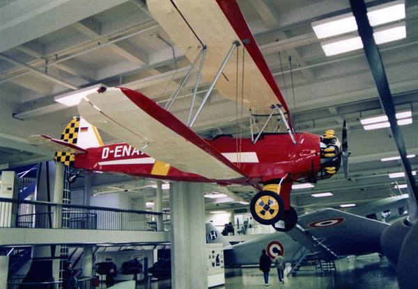 Vintage red biplane hanging from the ceiling of the Deutsches Museum, visitors below