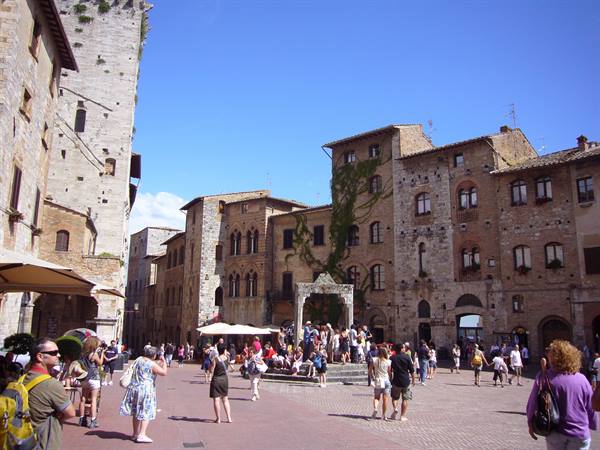 Tourists crowd the square in San Gimignano among medieval towers and stone buildings
