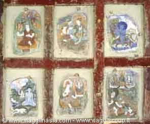 Six faded Buddhist murals framed in red on a weathered wall