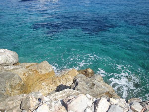Clear turquoise water with foam over sunlit limestone rocks
