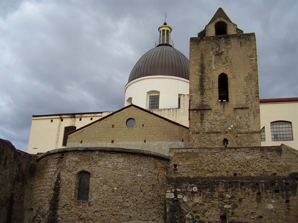 Stone bell tower and church dome beneath cloudy sky