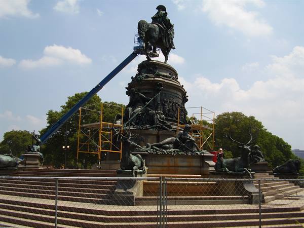 Bronze equestrian monument under restoration, surrounded by scaffolding and a crane