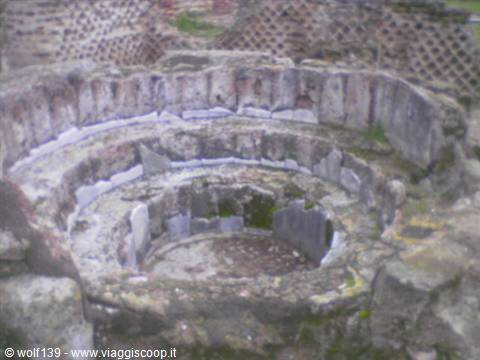 Ancient circular stone basin with concentric tiers among Roman ruins under soft light