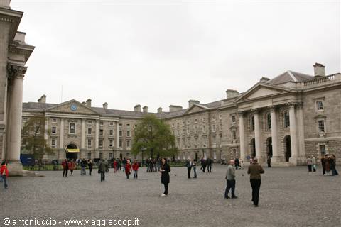 Trinity College Dublin cobbled quadrangle, grey stone Georgian buildings, pedestrians under cloudy sky