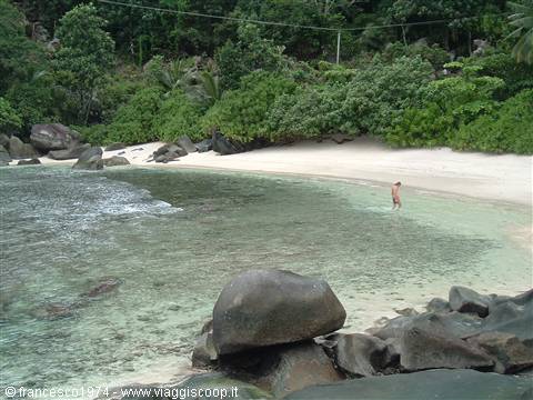 White sand beach with granite boulders and clear turquoise water