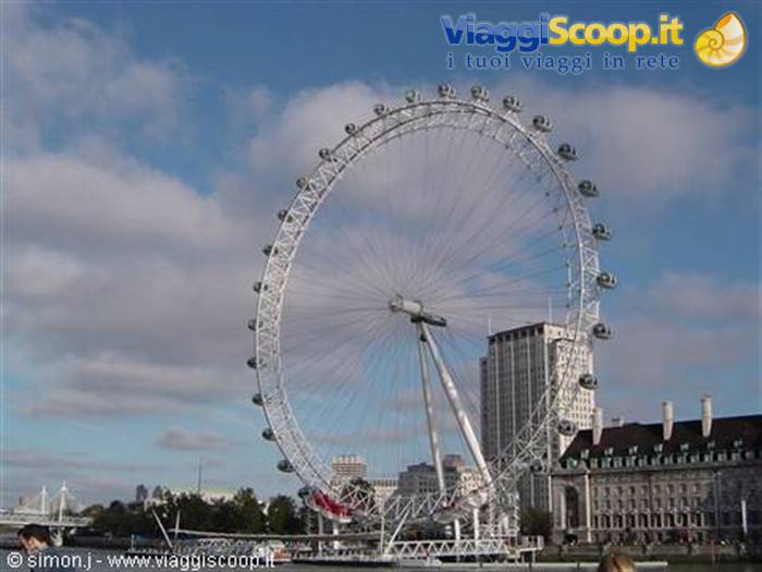 The steel London Eye rises over the Thames among clouds and buildings