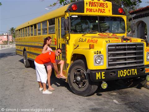 Man and woman boarding a yellow 'Pastores por la Paz' bus in bright sunlight