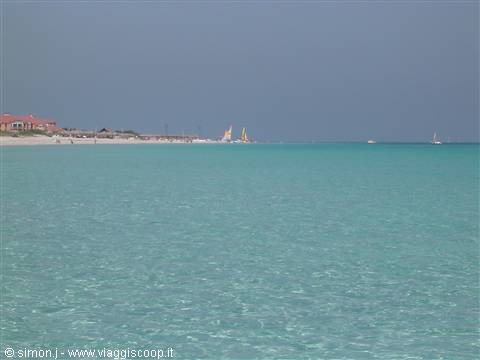 Turquoise sea with yellow sailboats in front of beach and resort