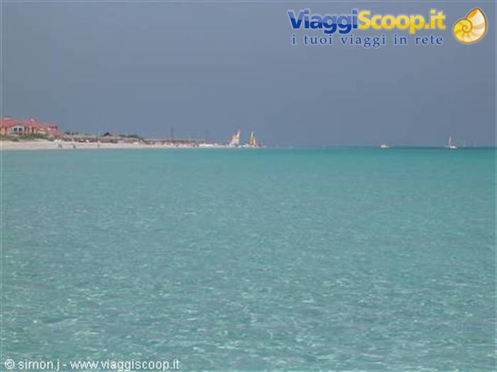 Turquoise sea with yellow sailboats in front of beach and resort