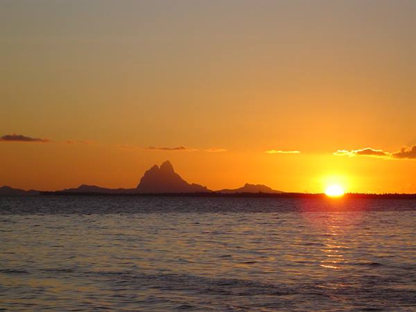 Sun touching the sea, dark silhouette of Le Morne Brabant on the horizon
